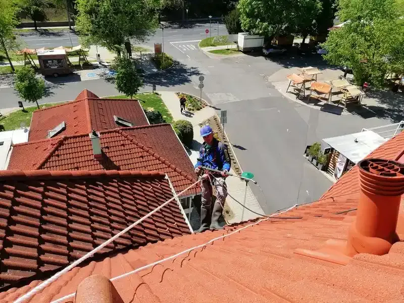 A képen egy tetőmosást végző szakember látható alpin technikával.